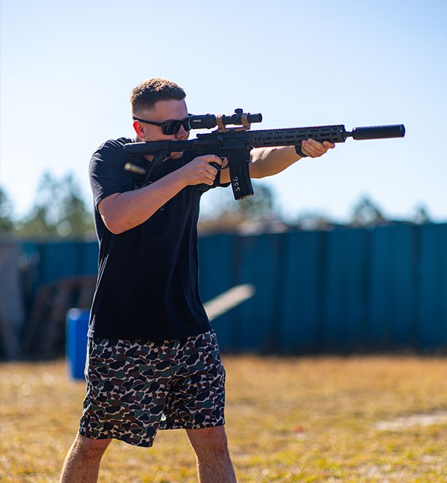Shooter aiming a suppressed AR on the range